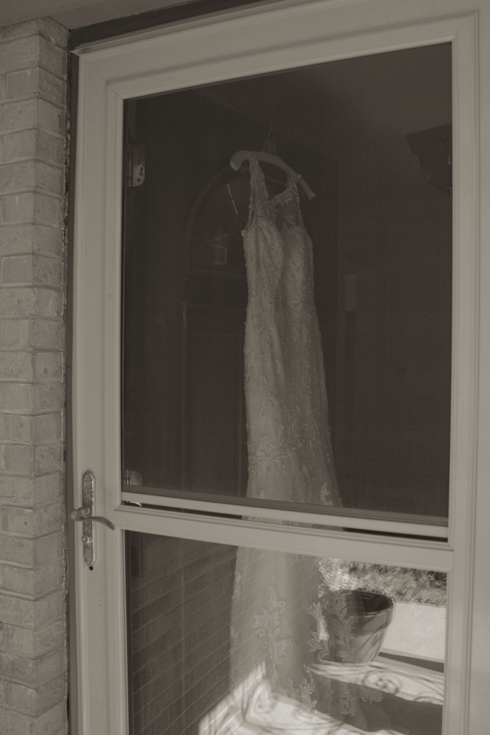 White wedding dresses hanging in display windows of a brick building exterior.
