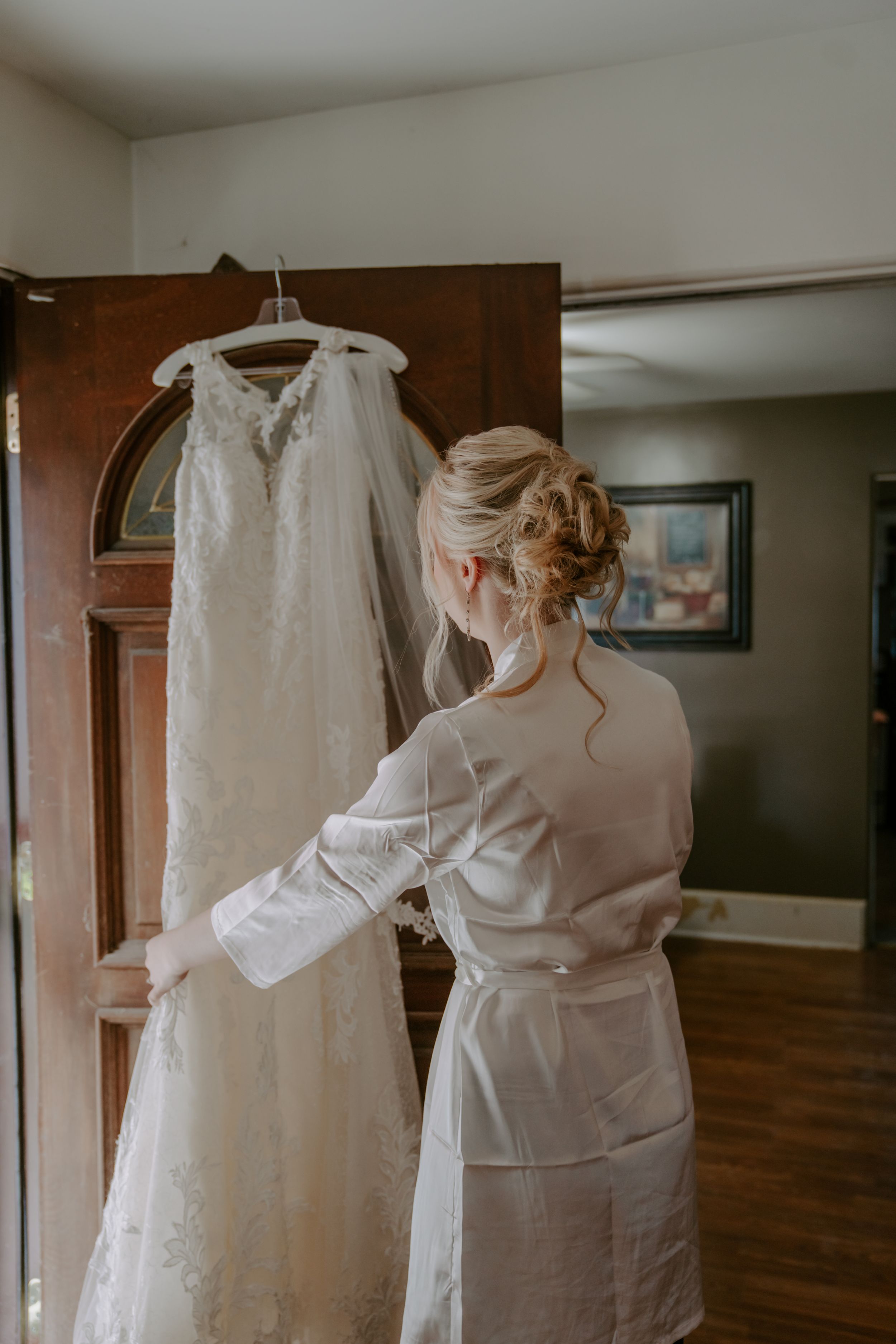 Wedding dress preparations in a room with natural light streaming through windows.