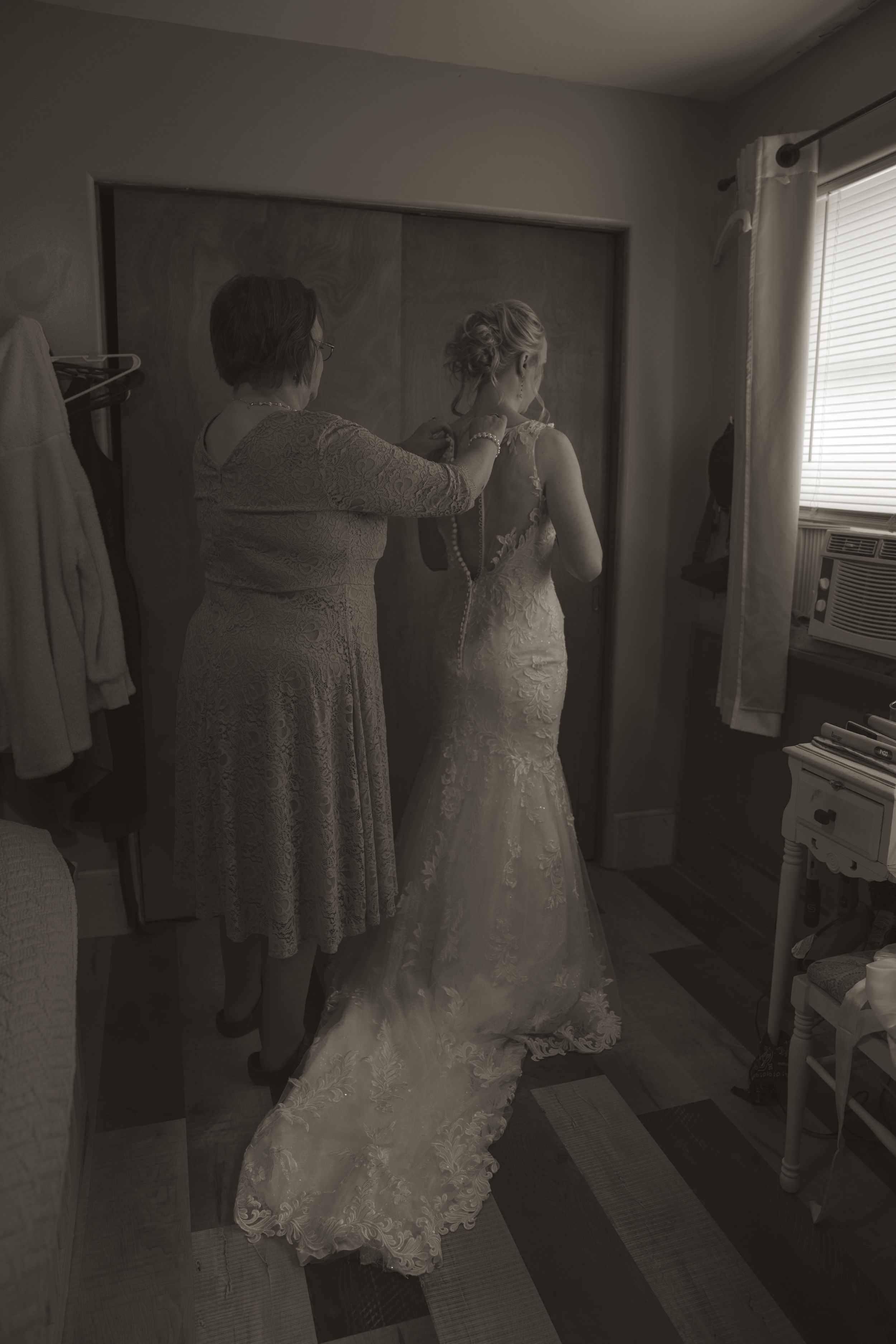 Multiple wedding dresses displayed in a room with soft, moody lighting.