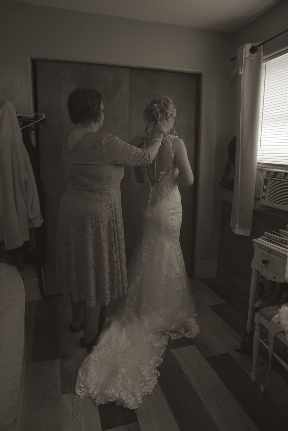 Multiple wedding dresses displayed in a room with soft, moody lighting.
