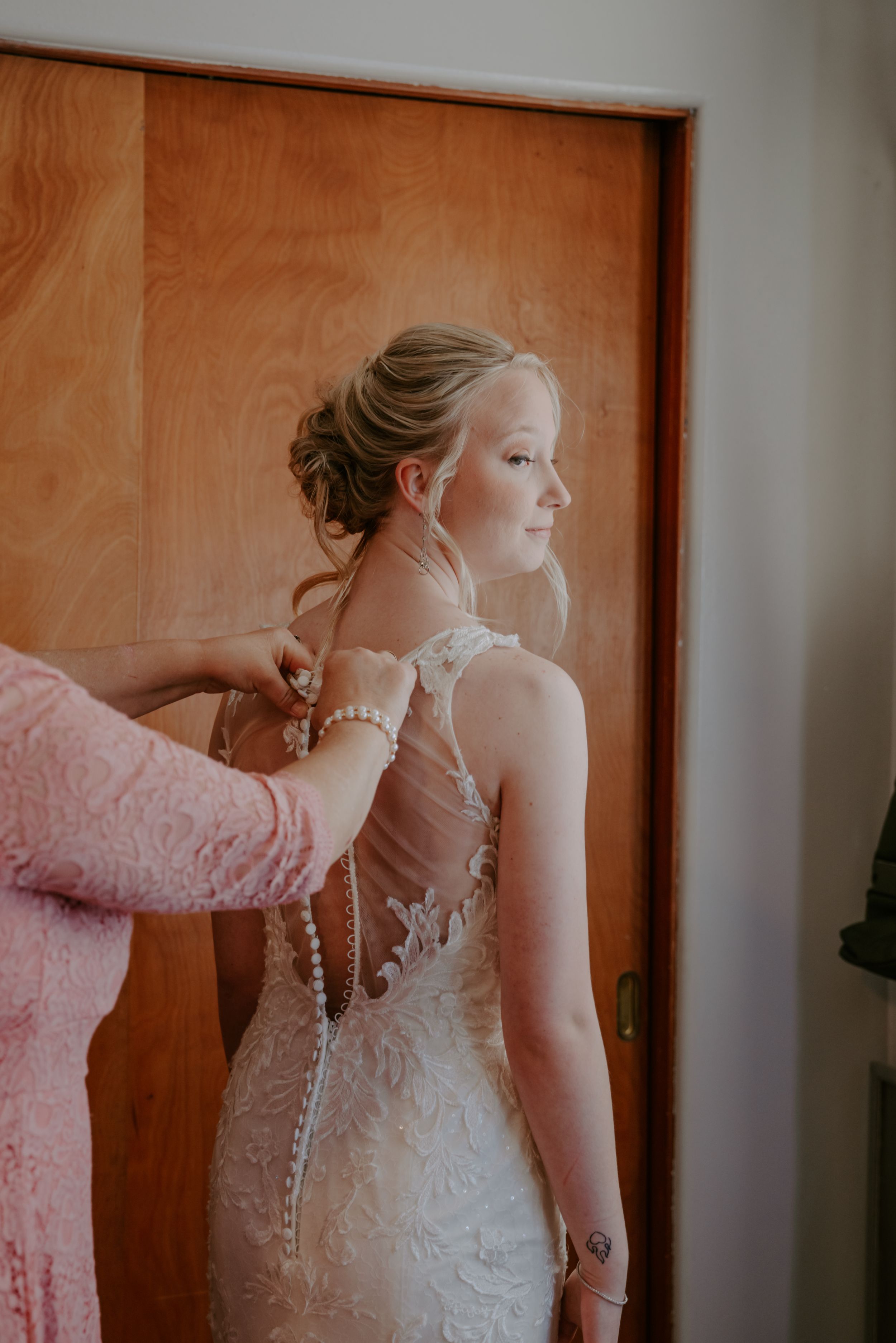 A detailed view of an elegant lace wedding dress with pearl buttons.
