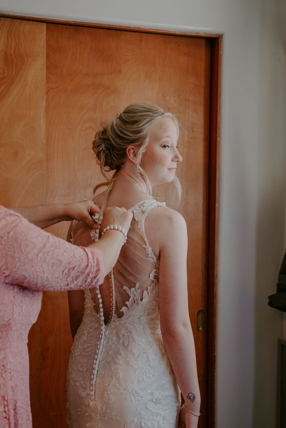 A detailed view of an elegant lace wedding dress with pearl buttons.