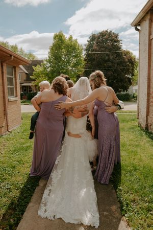 Wedding party in purple dresses walking together outdoors on a sunny day.