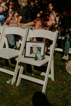White folding chairs set up on grass for an outdoor wedding ceremony.