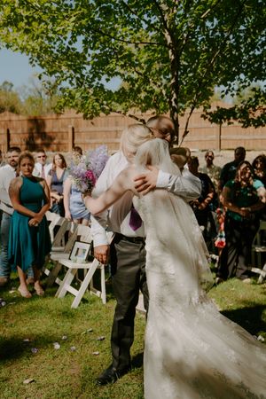 A couple shares their first dance surrounded by guests at an outdoor garden wedding.