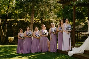 Bridesmaids in lavender dresses lined up outdoors during a summer wedding.