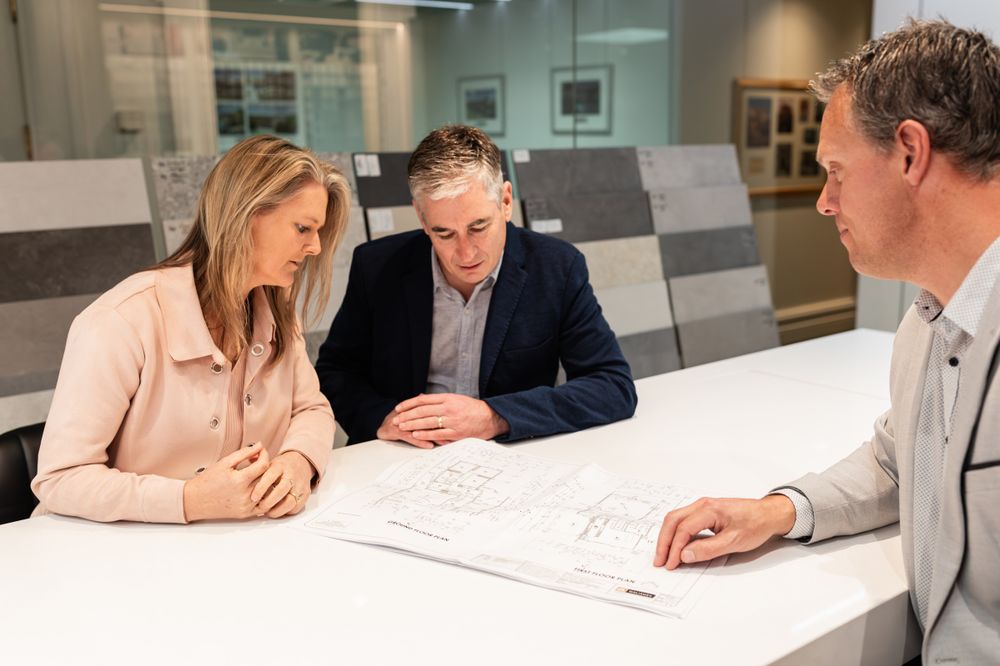 Professional team discussing blueprints at white conference table in modern office.