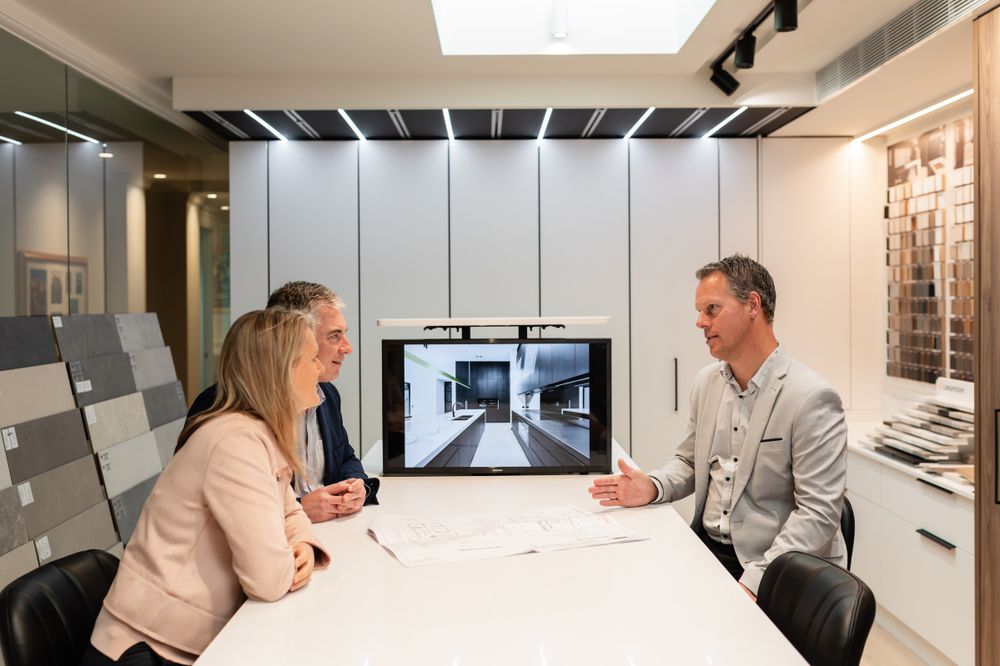 Office meeting with digital display showing interior design renders on screen.