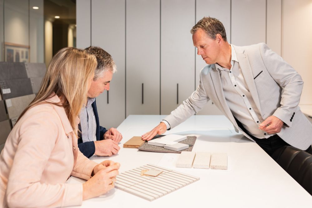 Business professionals reviewing architectural plans and documents on a white conference table.
