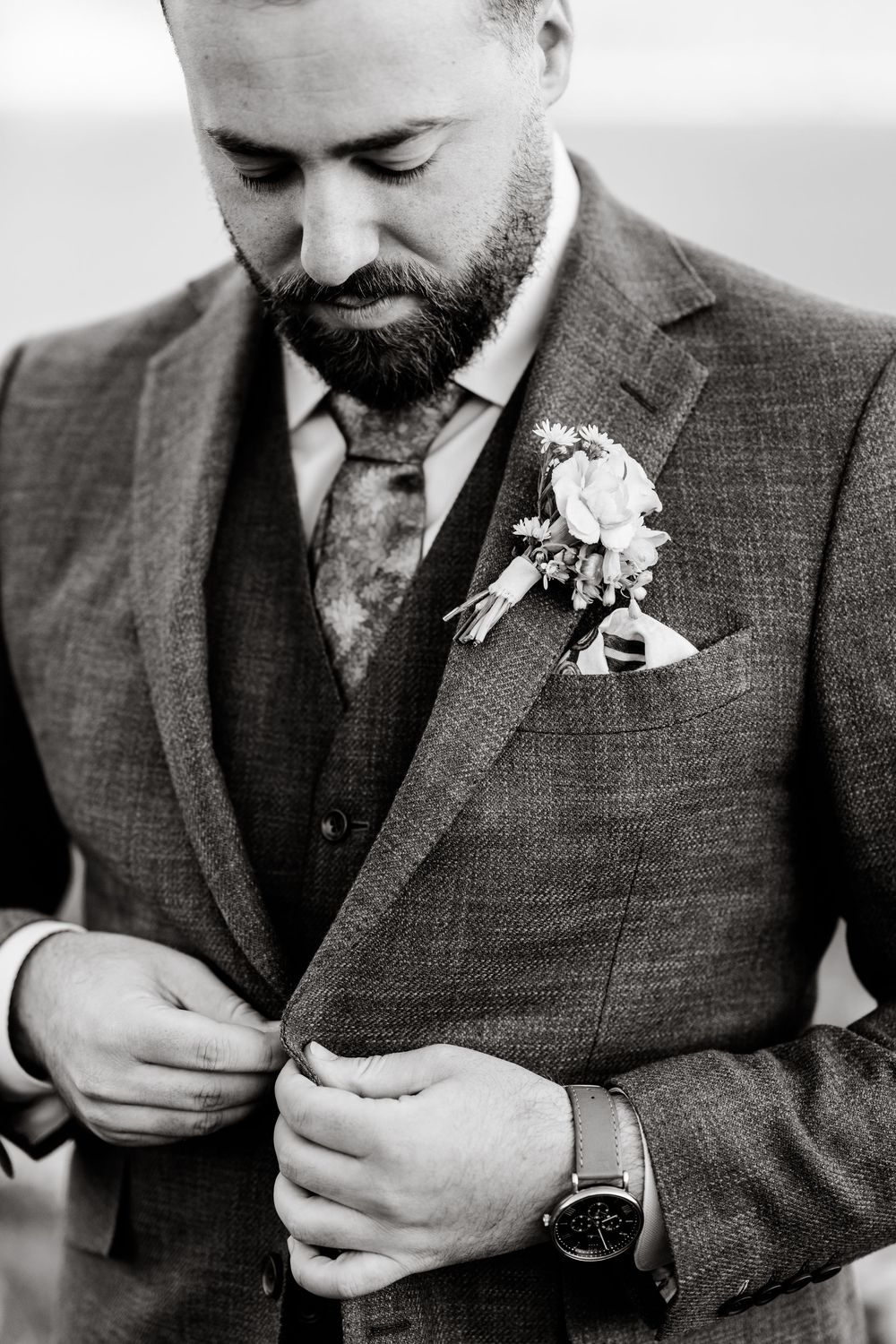 Black and white detail shots of a groom in a tweed suit adjusting his sleeve cuff.