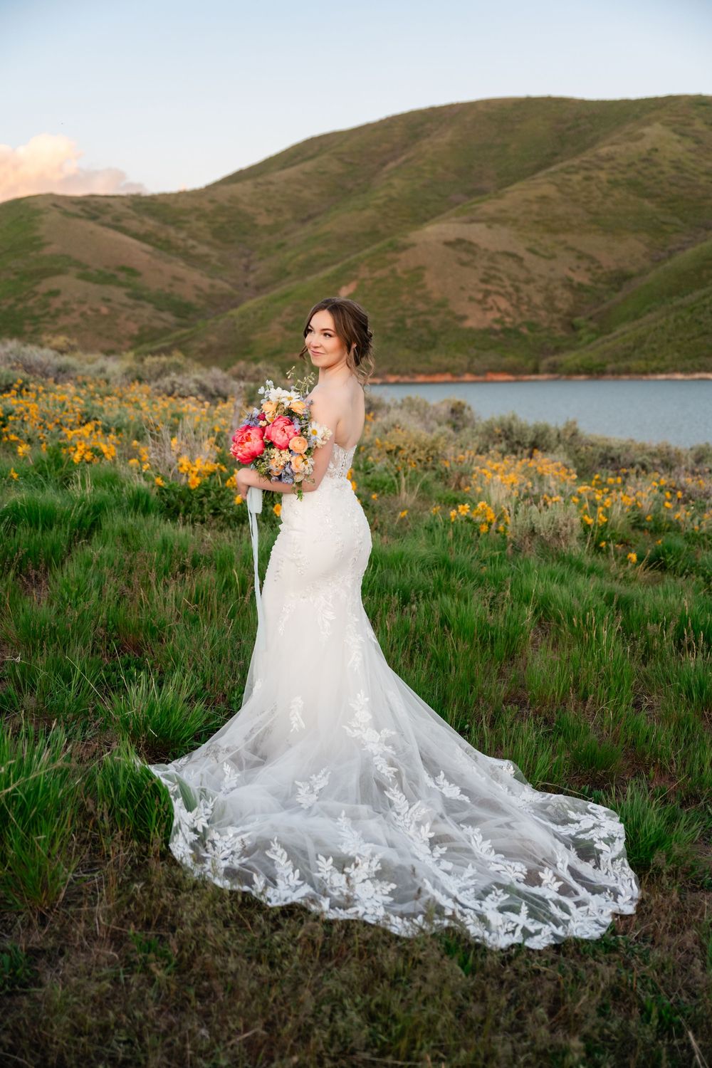 Scenic bridal portraits in a rolling green hillside landscape with a flowing lace wedding gown train.