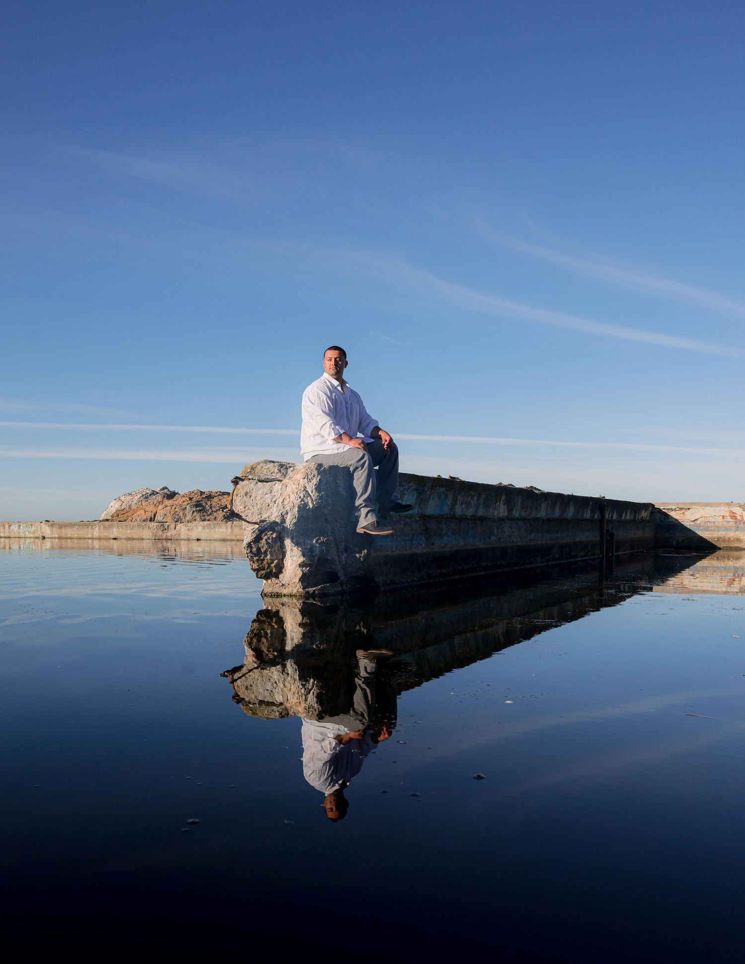 Figures sit atop dramatic salt formations at the Great Salt Lake in Utah reflecting in mirror-like waters at sunset.
