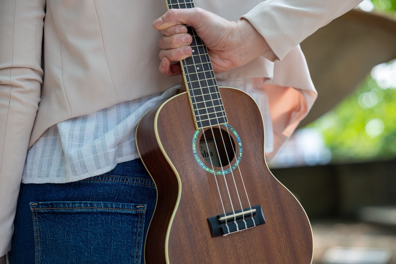 Close-up of ukulele held by musician outdoors — artistic instrument detail photography