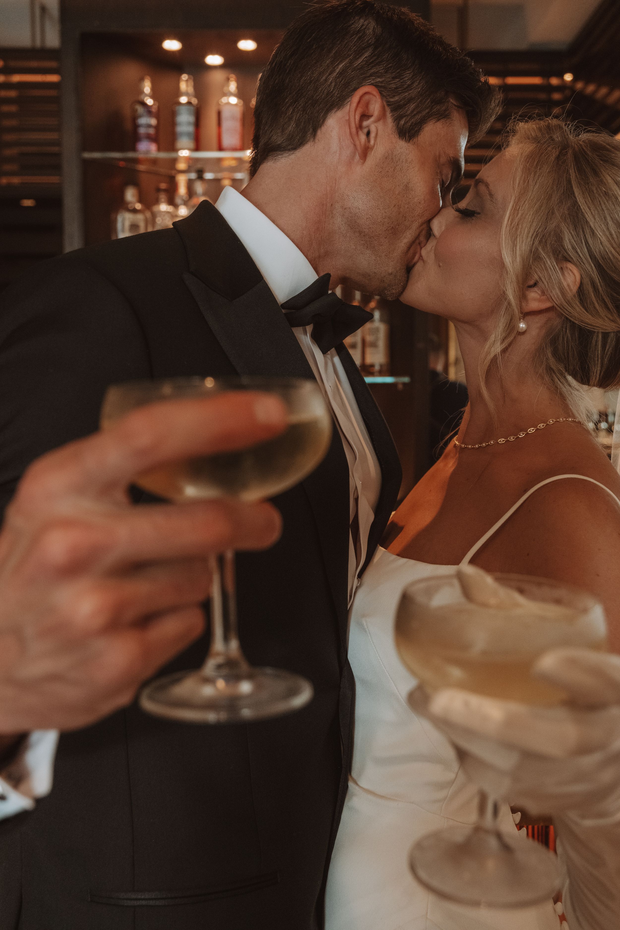 A romantic couple shares an intimate moment while holding glasses during an elegant evening reception.