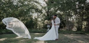 A couple in romantic poses shares intimate moments in a sun-dappled wooded setting during a wedding photoshoot.