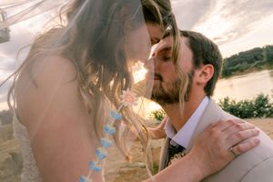 Sunset wedding portrait with veil flowing in the breeze as couple shares an intimate moment.