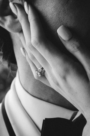 Black and white close-up detail shot of an engagement ring on a hand.