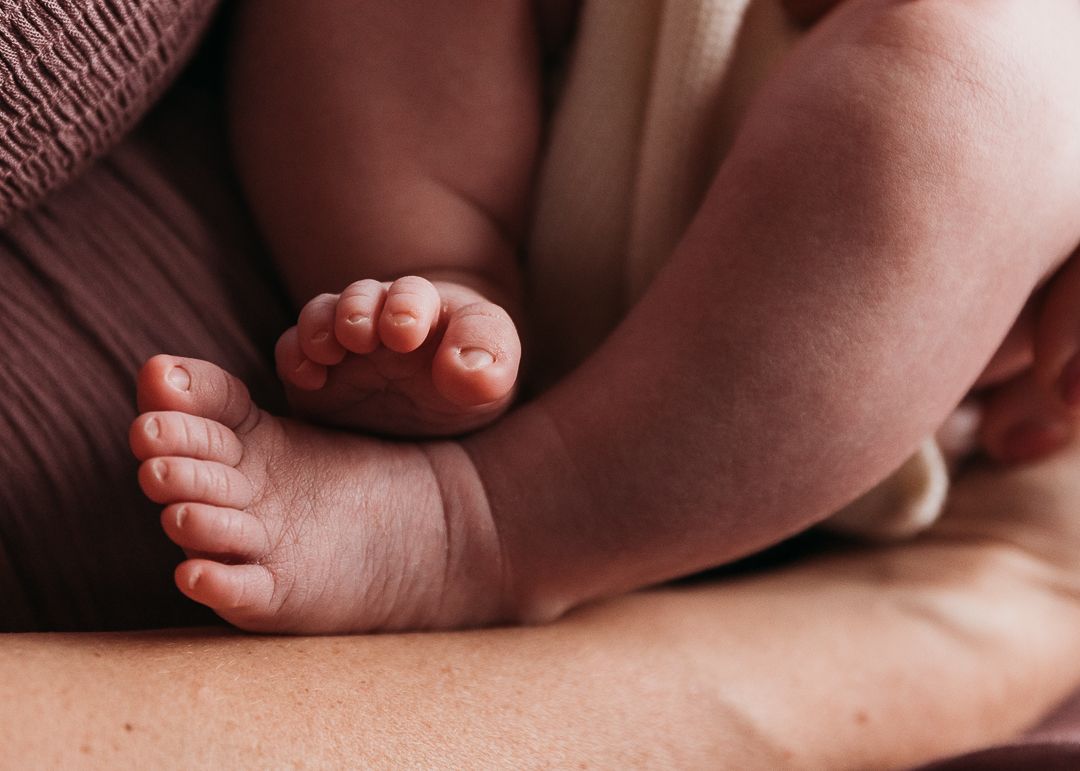 Close-up photo of tiny baby feet resting on a soft pink surface.