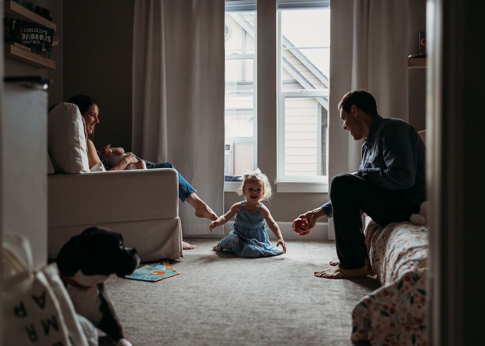 Family relaxing together in a cozy room with natural window light.
