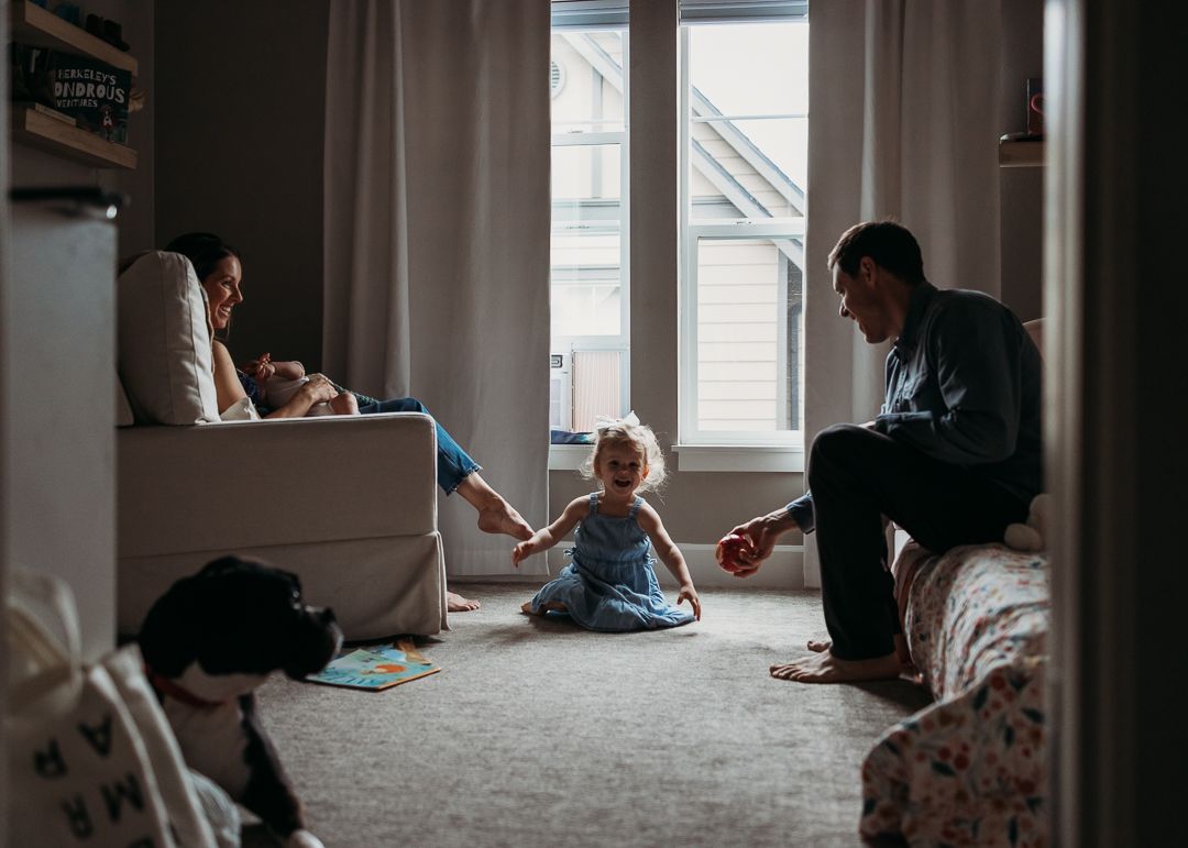 Family relaxing together in a cozy room with natural window light.