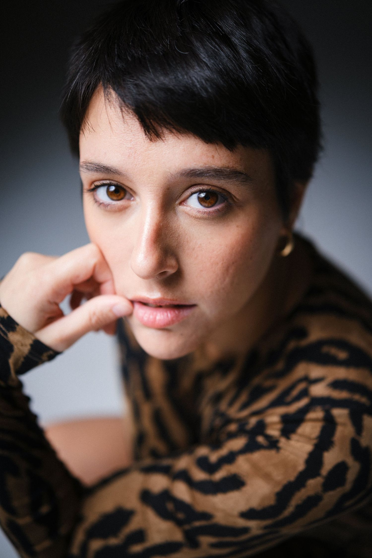 Close-up portrait in animal print top against dark background.
