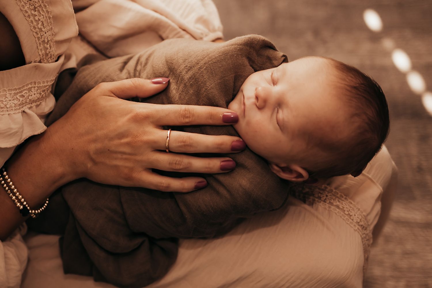 baby boy in a brown swaddle being held by his mom
