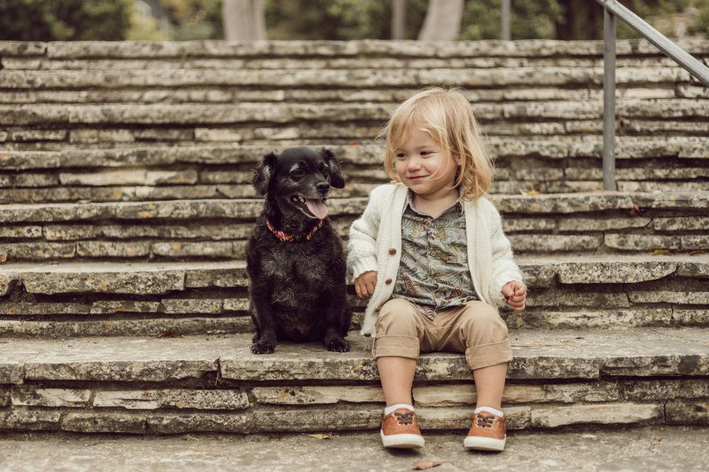 Little girl sitting on steps with her small black dog