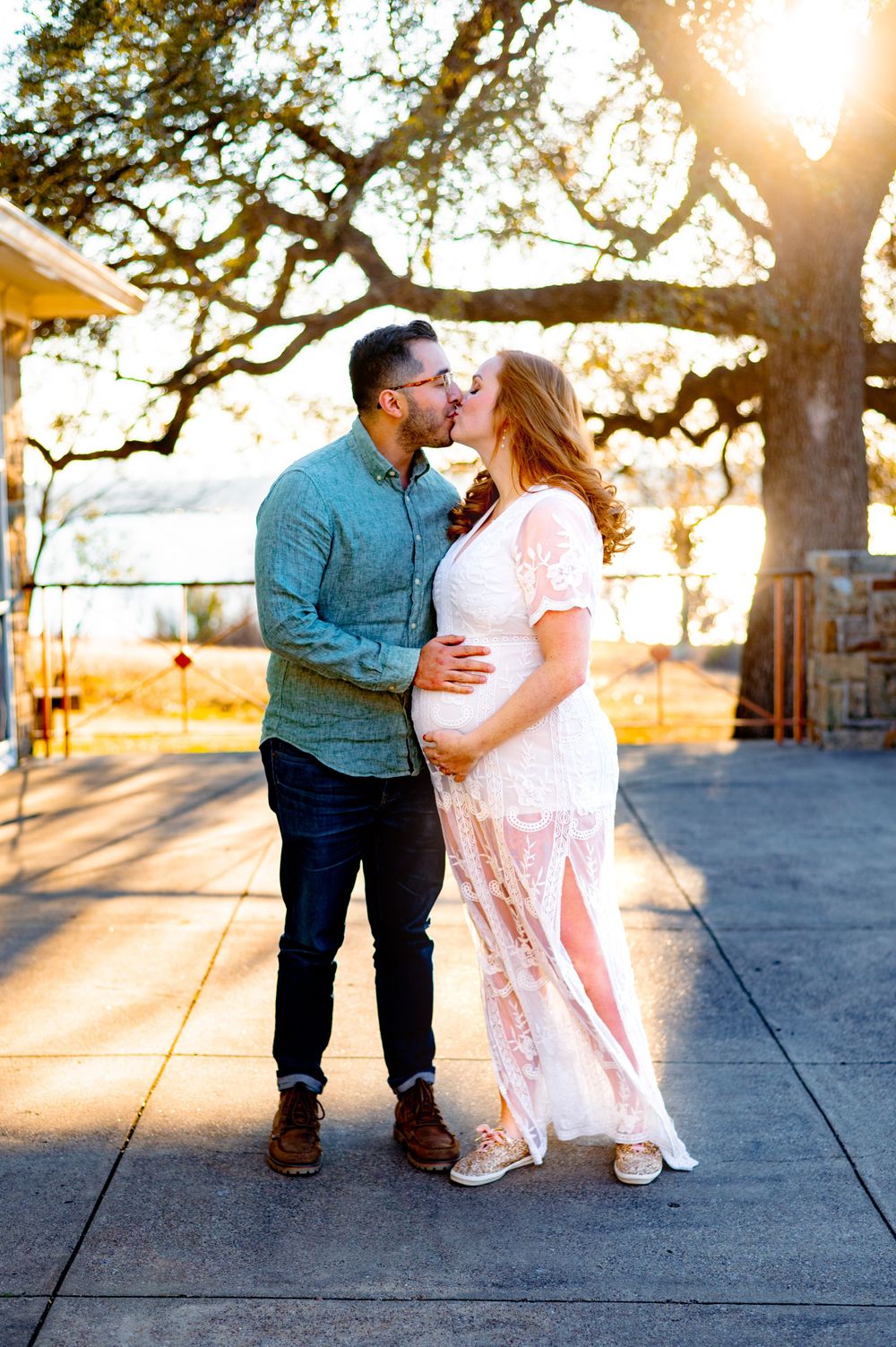 Biracial couple kiss holding baby bump during winfrey point maternity photo session at sunset in dallas by mesquite, tx family photographer