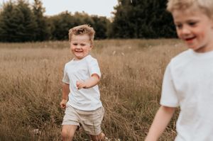 twee broers die lopen door een veld met hoge grassen in een veld in Roeselare tijdens een gezinsshoot.