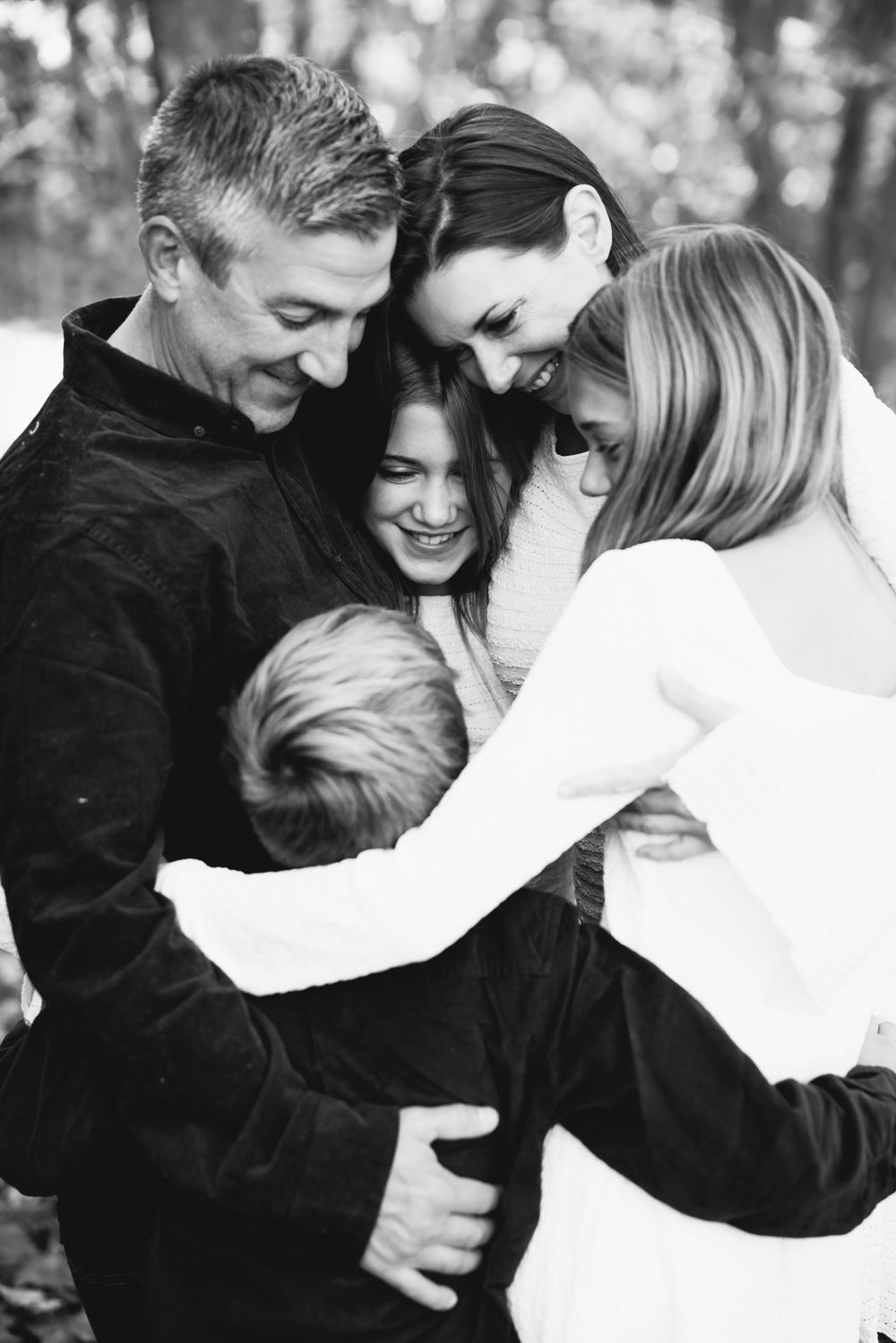 Black and white candid family photo showing joyful embraces and genuine laughter.