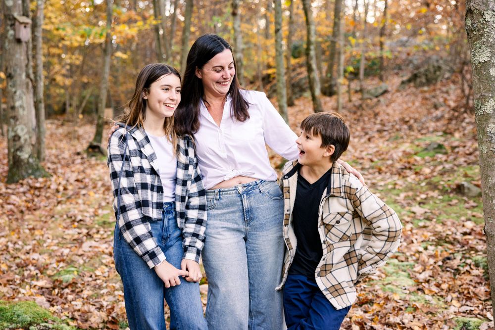 Candid moment of laughter in a fall forest setting with matching plaid shirts.