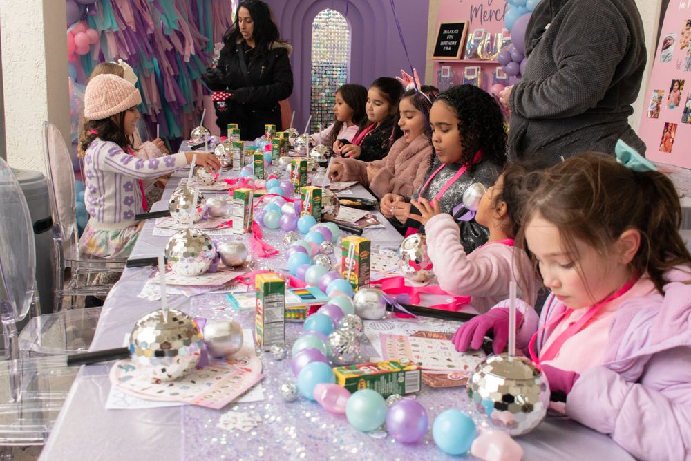 Children seated at long table enjoying party activities with decorative elements.