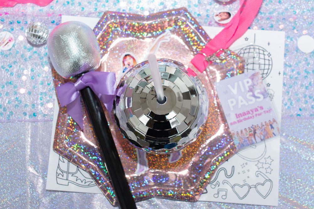 Close-up of party decorations including microphones and disco ball on a sparkly background.