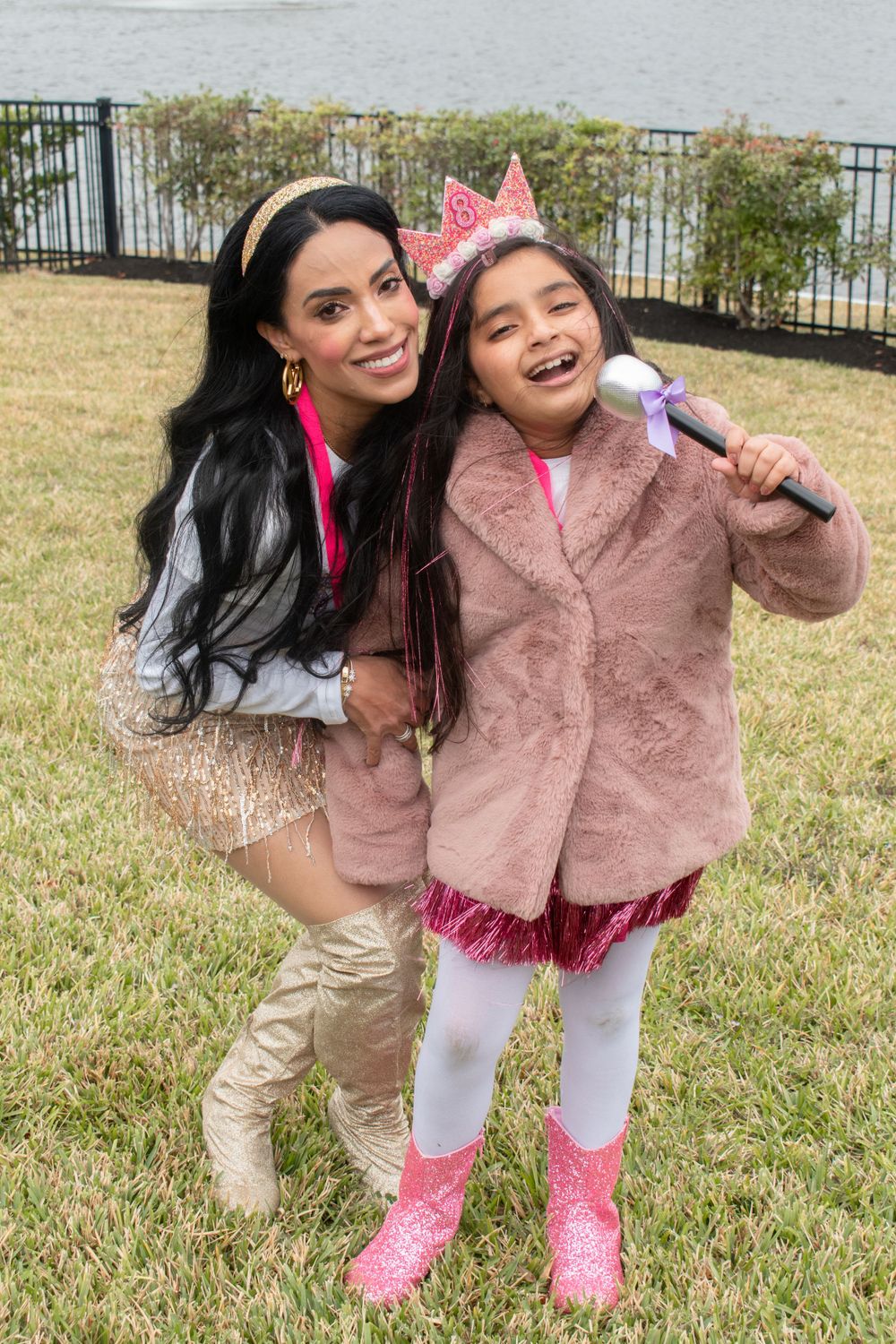 A celebratory outdoor photo of two people wearing pink and sparkly party attire.