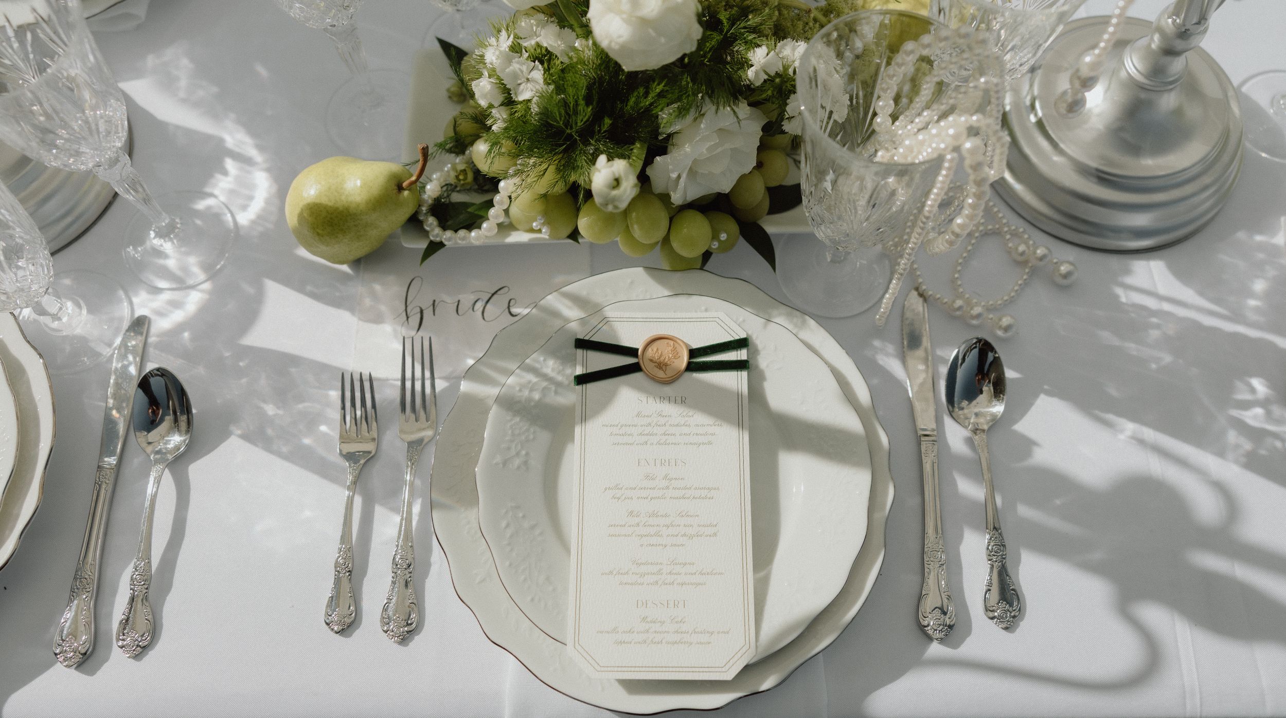 Elegant wedding place setting with white linen, silverware, and fresh floral centerpiece on a formal dining table.