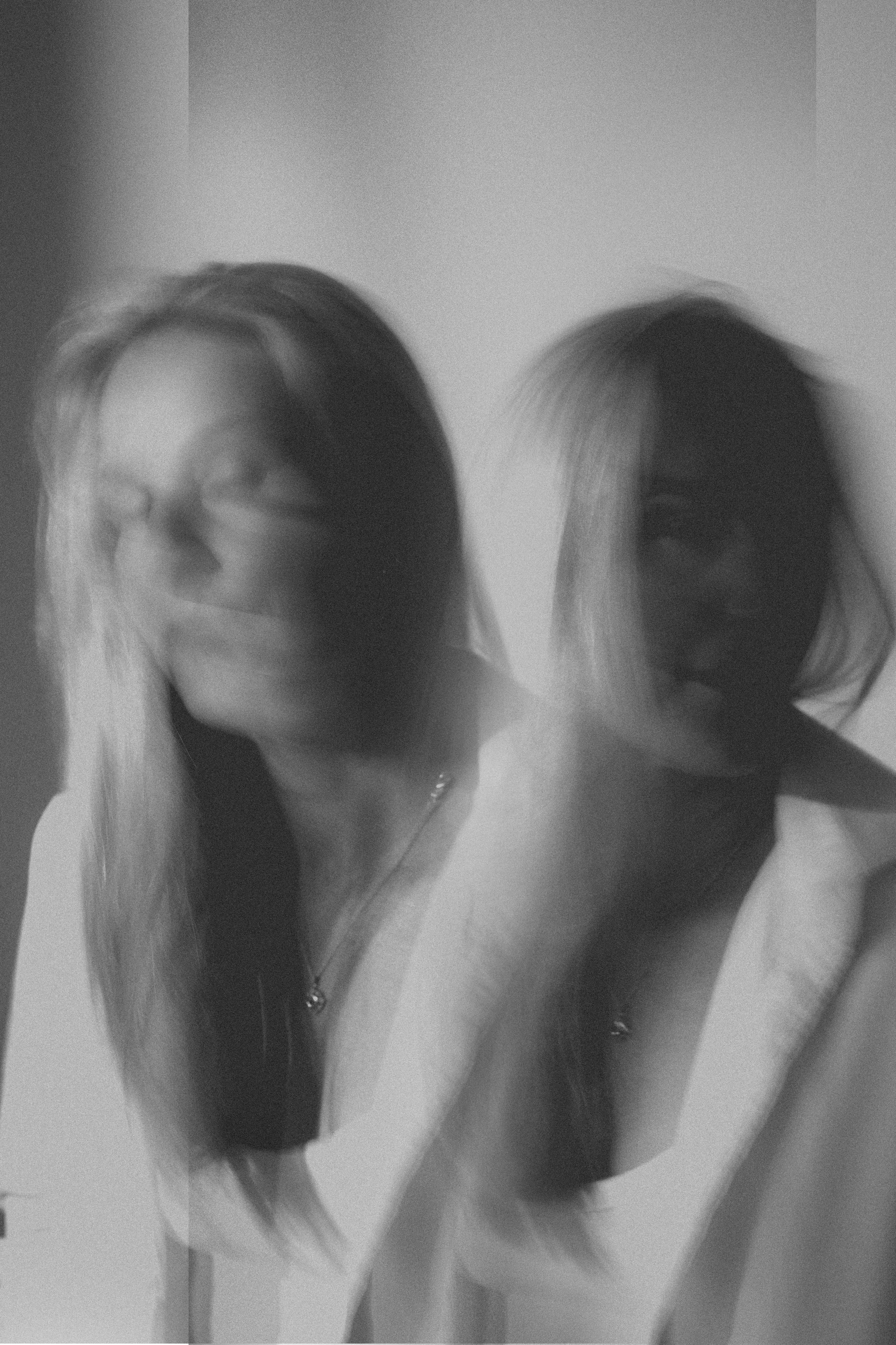 Blurred black and white double exposure portrait of a blonde woman creating an artistic ghostly effect.