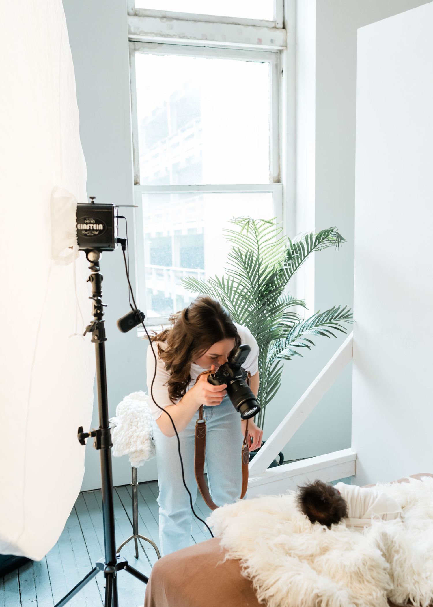 Behind the scenes of photographer working with professional lighting equipment in bright studio space.