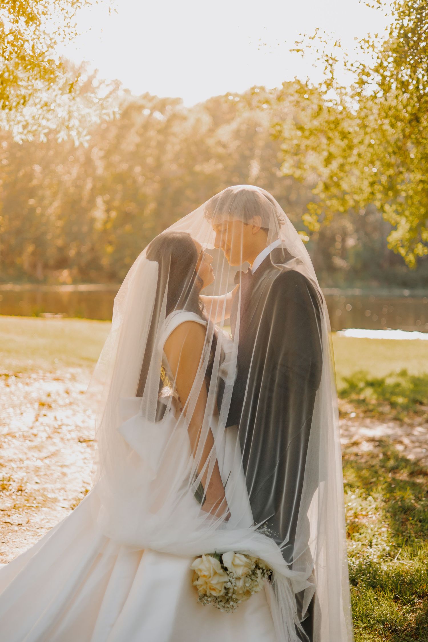 Ethereal wedding scene with veiled figures in golden sunset light among autumn leaves.
