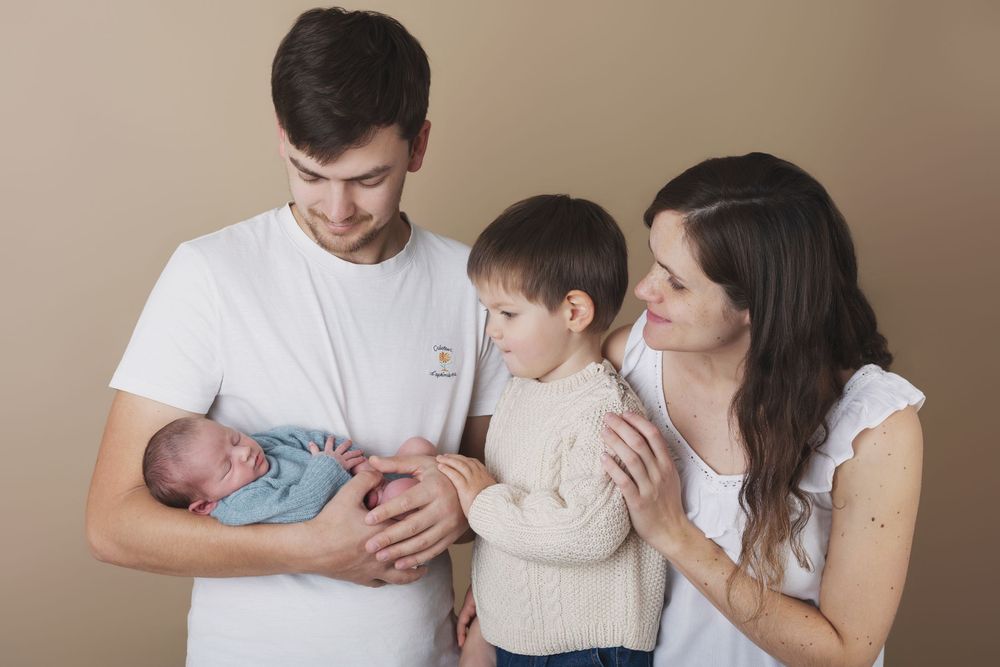 Parents et enfant accueillant leur nouveau-né lors d'une séance photo famille et naissance en Charente.