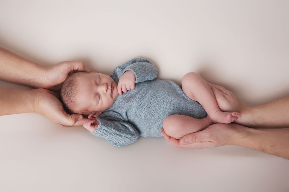 Nouveau-né photographié dans les mains de ses parents lors d'une séance naissance à Fléac.