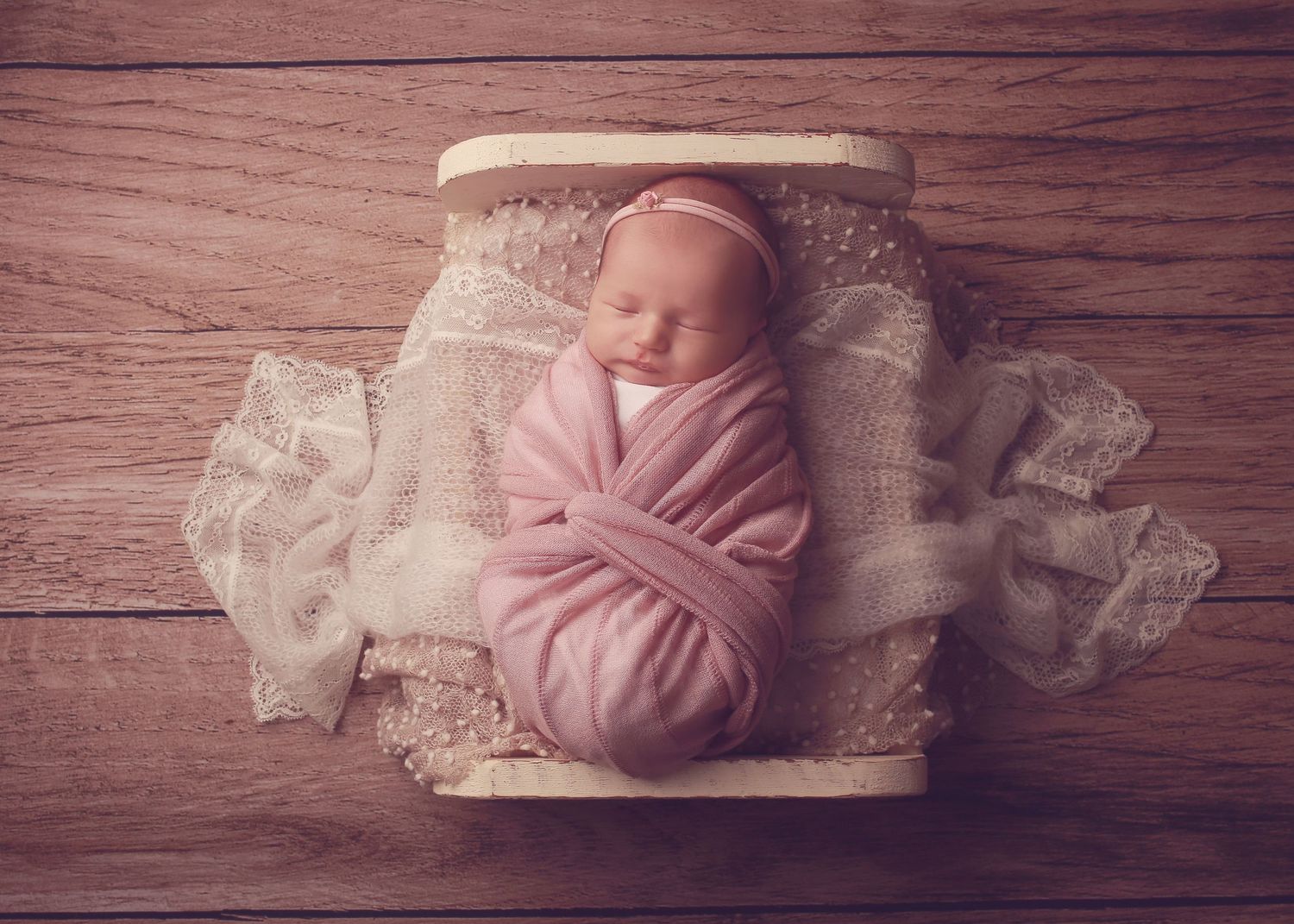 A peaceful newborn baby girl wrapped in soft fabrics, captured in a serene and intimate setting, showcasing the delicate beauty in photo