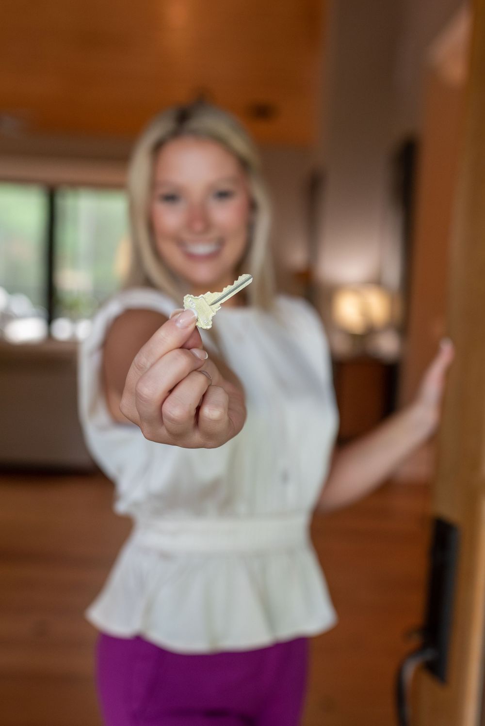 Person in white top showing excitement while holding up keys in wooden-accented room at a business branding session.