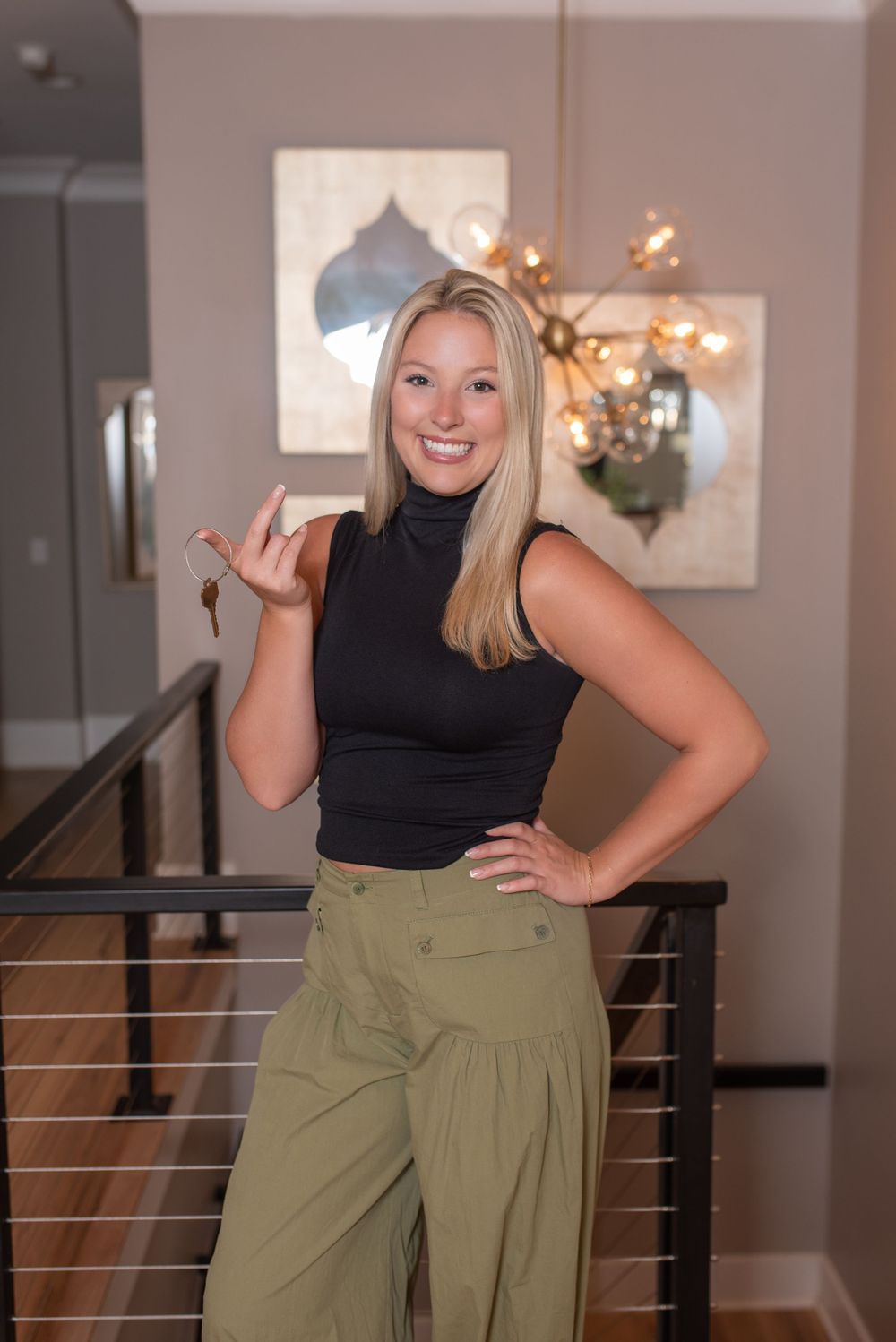 Woman in black top and olive pants posing in series of professional business photos against interior background.