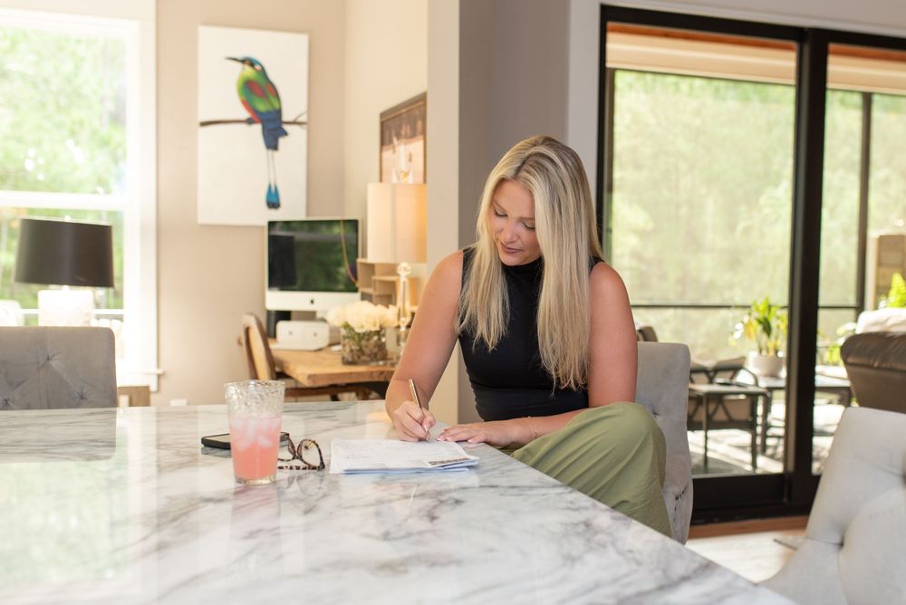 Modern home interior with marble countertops and large windows overlooking green outdoor views at a business branding session.