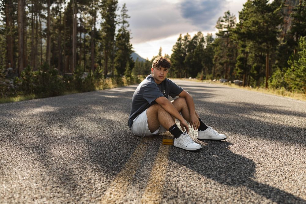 A person lies injured on a gravel road while another person provides medical assistance during an emergency.