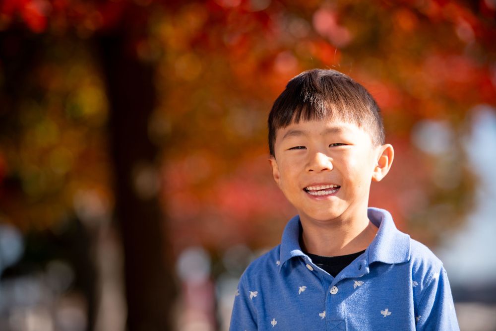 Young boys smiling and laughing under bright fall foliage.