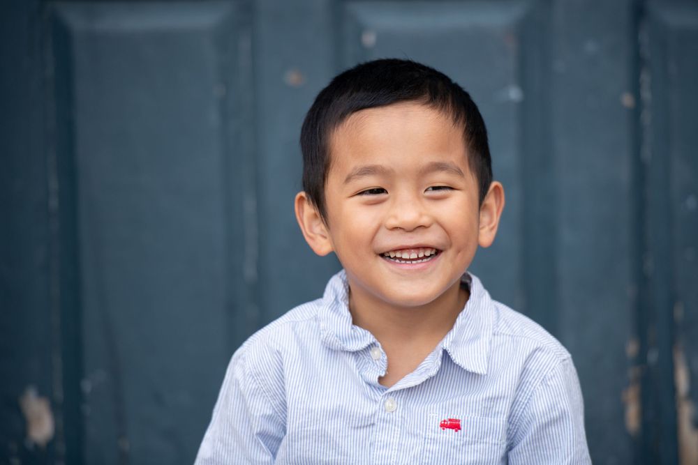 Children posing against blue wall for casual portrait series.