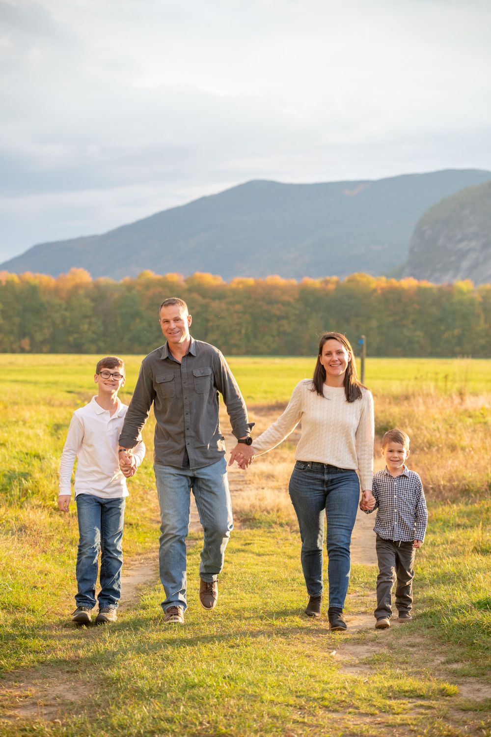 Family walking together on a path with mountains and autumn colors in the background.