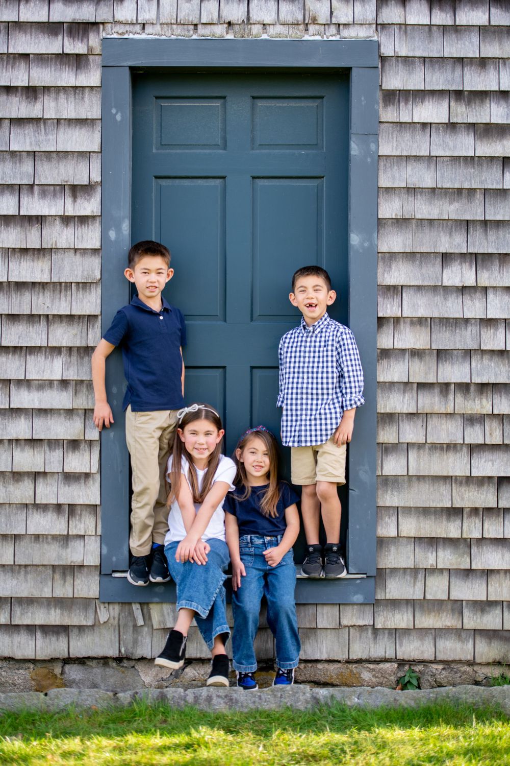 Children posing together by a weathered building with blue doors.