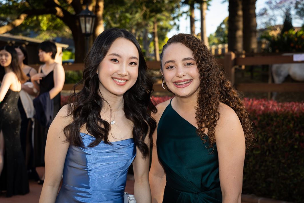 Sydney Event Photography - Two friends in formal dresses, one in blue and one in green, smile together at an outdoor evening event.